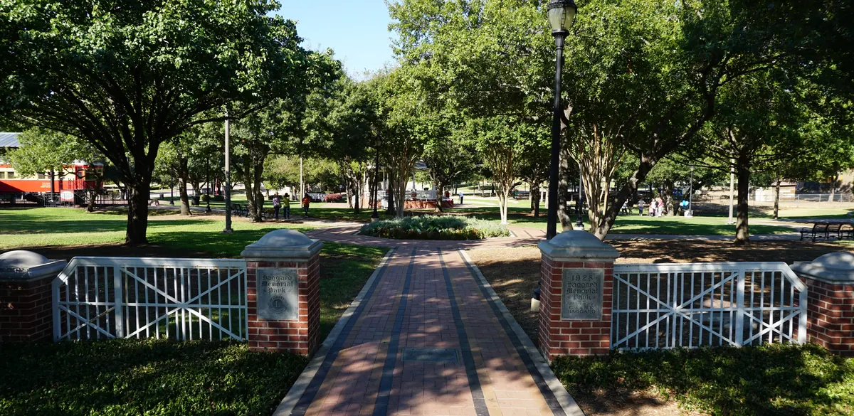 Entrance gates, a brick path and trees at Haggard Park in Plano.