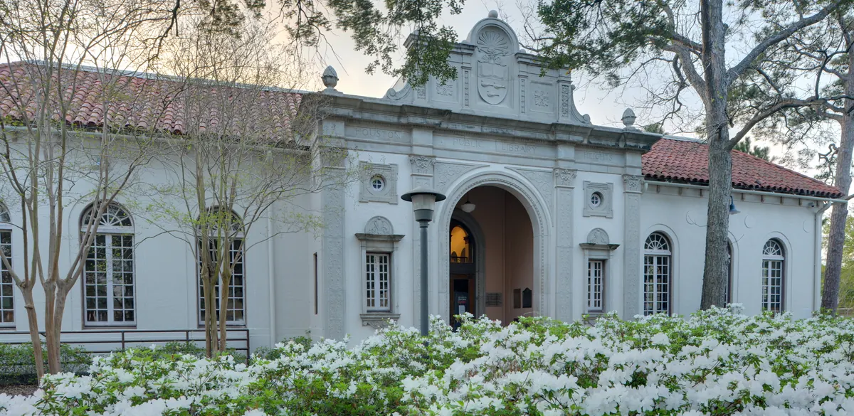 The front of Heights Neighborhood Library in Houston, with flowering plants and trees.