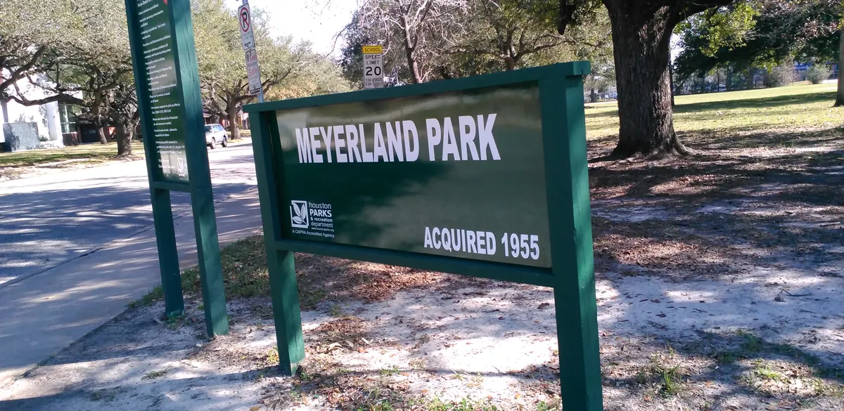 Meyerland Park entrance sign beneath a large tree in Houston.